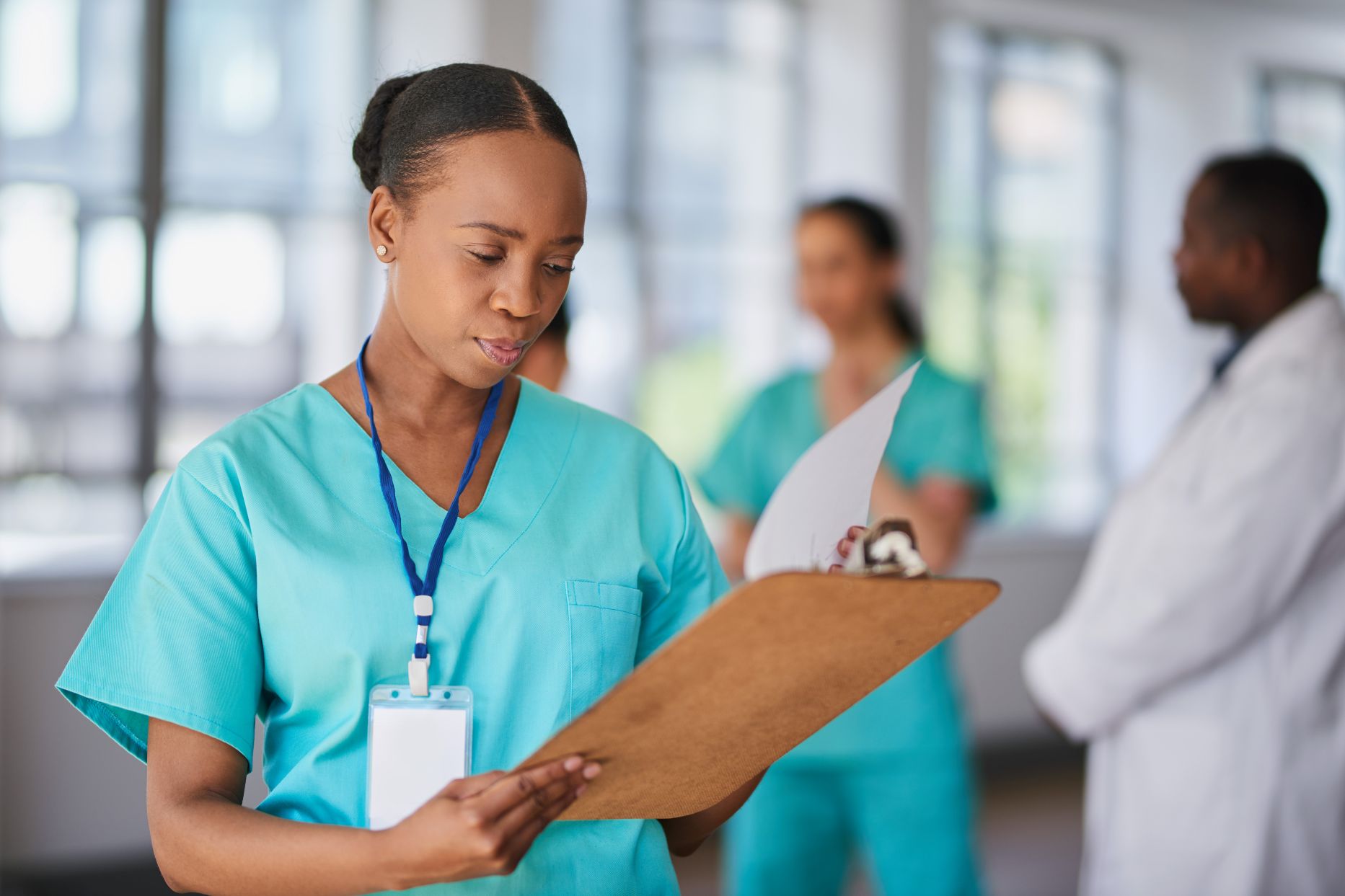 A woman wearing scrubs in a health-care setting reviews a chart