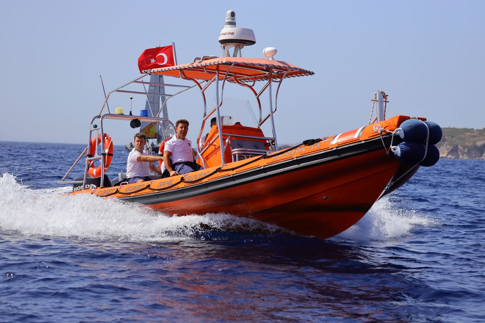 A small boat flying the Turkish flag moving through the sea.