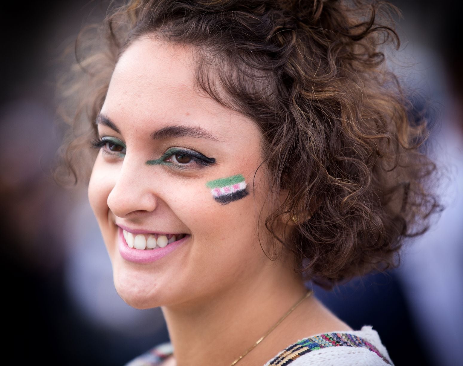 A young woman with the Syrian flag painted on her cheek
