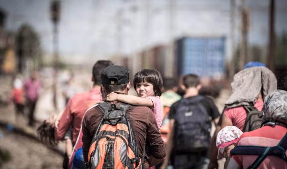 A child looking at the camera while being held by a man