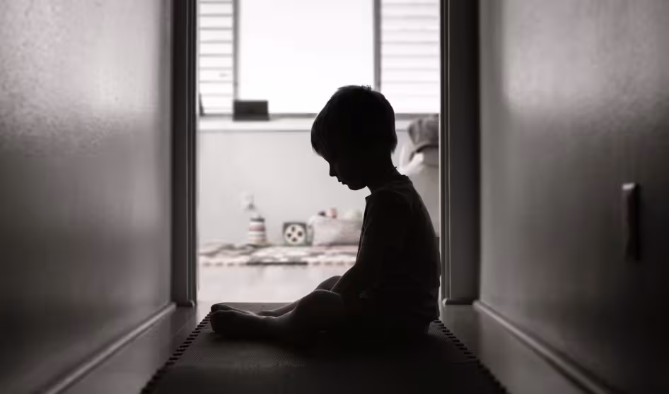 A silhouette of a young child looking sad and alone