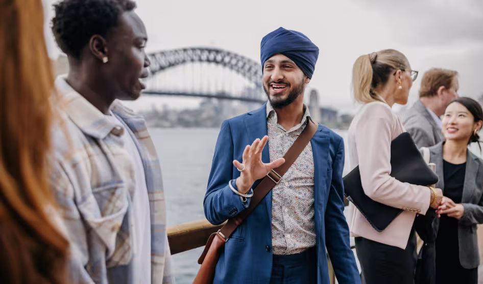 People of different ethnic backgrounds engage in a lively discussion, against the backdrop of Sydney Harbour Bridge