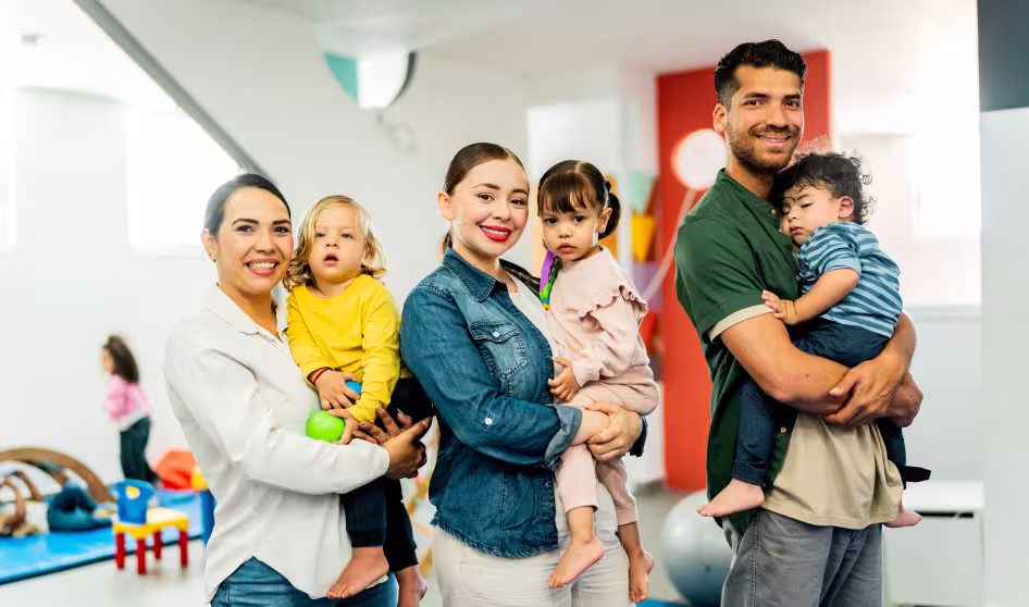 Three parents holding toddlers in a preschool classroom