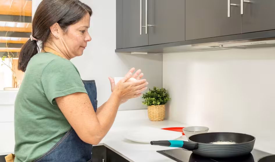 A woman makes arepas in the kitchen.