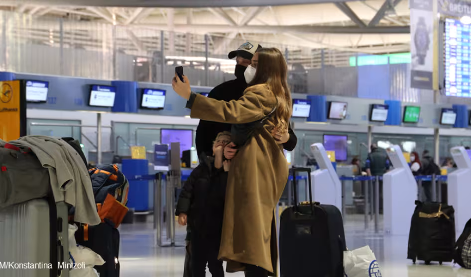 People wearing face masks take a selfie at an airport