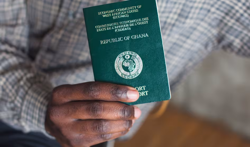 A green passport from Ghana held in a person's hand.