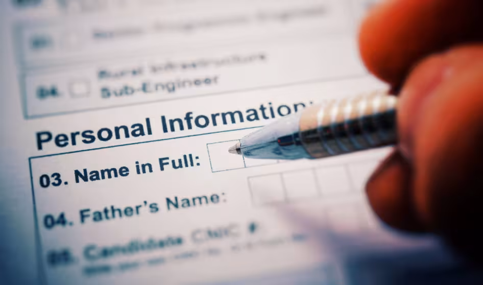 A pen poised above a form reading "Personal Information: Name in Full"