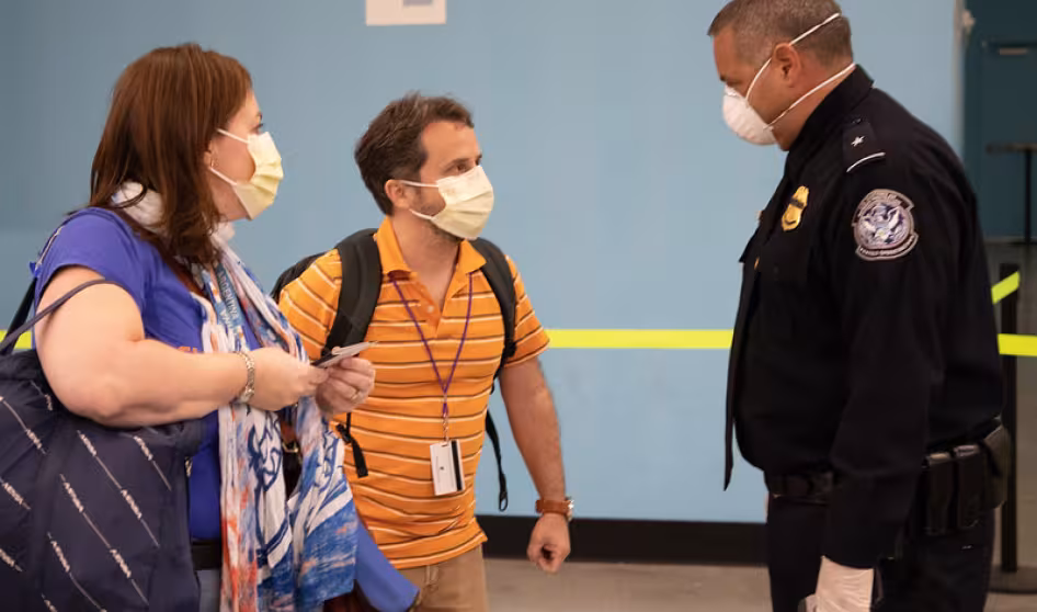 Officer and travelers wearing PPE at Port Everglades, Florida