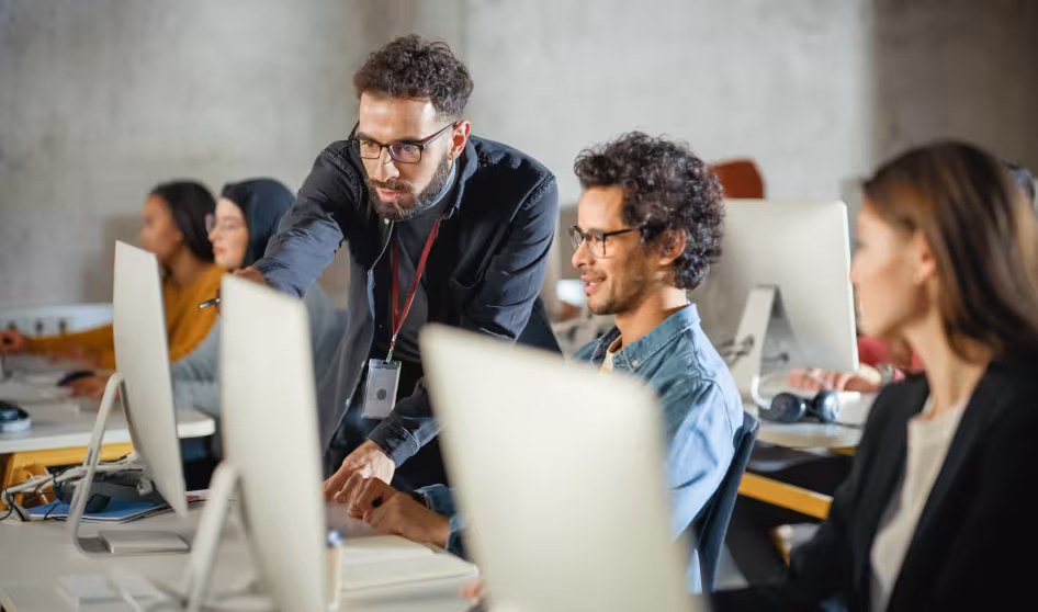 Image of teacher helping group of students at their computers