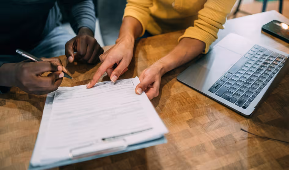 Image of the hands of two people at a desk going over paperwork
