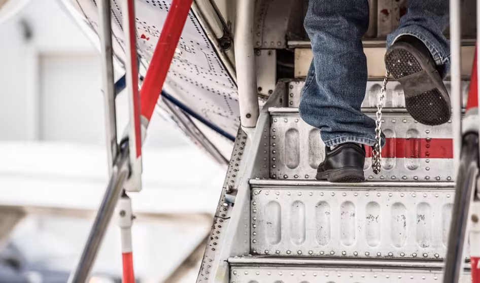 Image of unauthorized immigrant in shackles entering plane for deportation flight