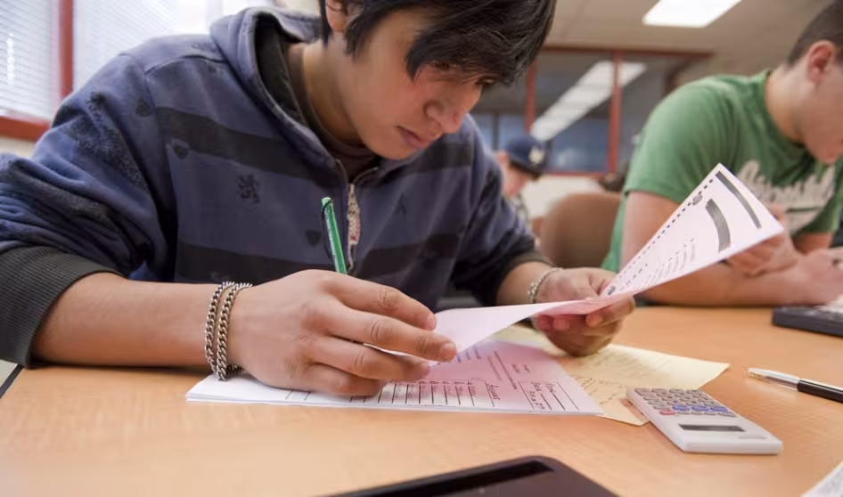 Student looking over a paper at a desk