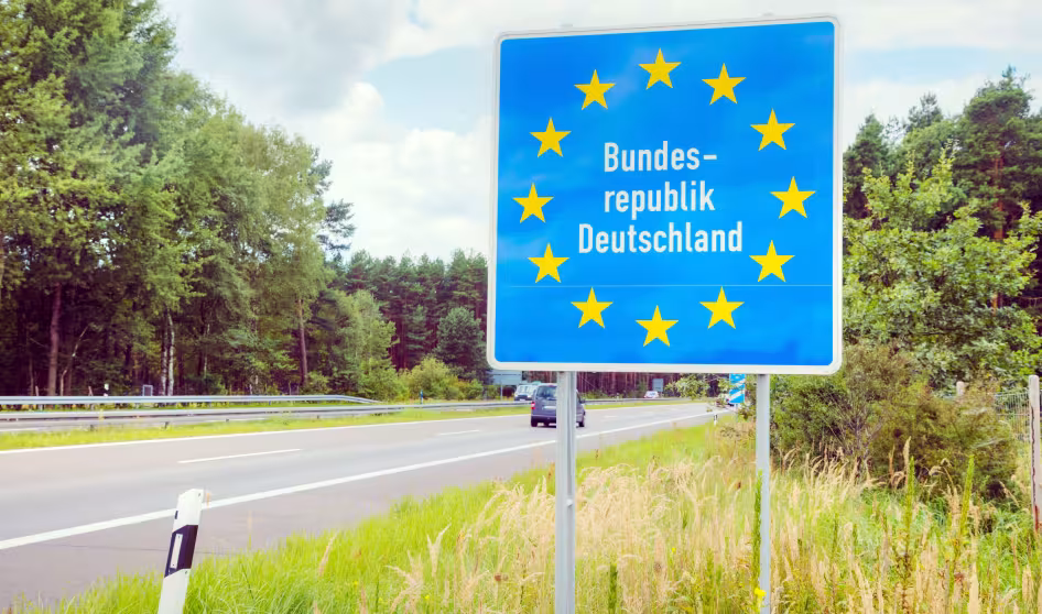A German border sign next to a road