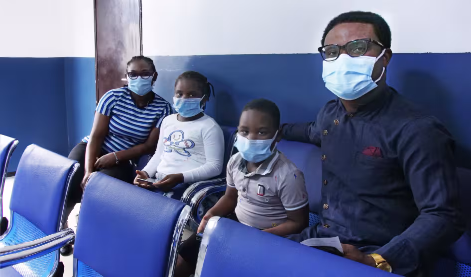 Two adults and two children wearing face masks at a migration health centre in Nigeria