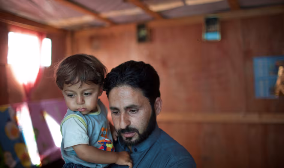 Syrian father holds his young son in Lebanon