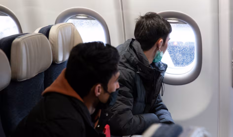 Two people on an airplane looking out the window