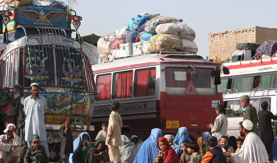 Returned Afghan refugees wait by the buses in Kabul that will take them back home.