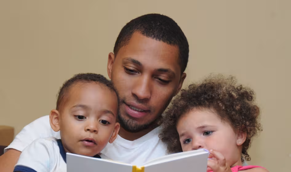 An immigrant father reading with his children.