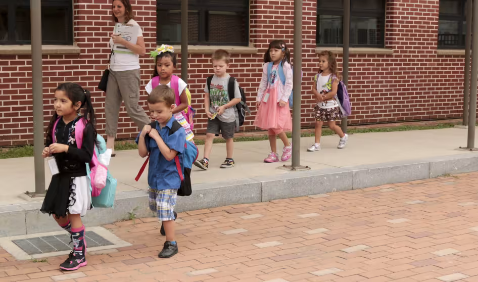 Young students walking with their teacher.