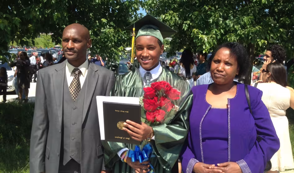 A refugee student with his family at graduation.