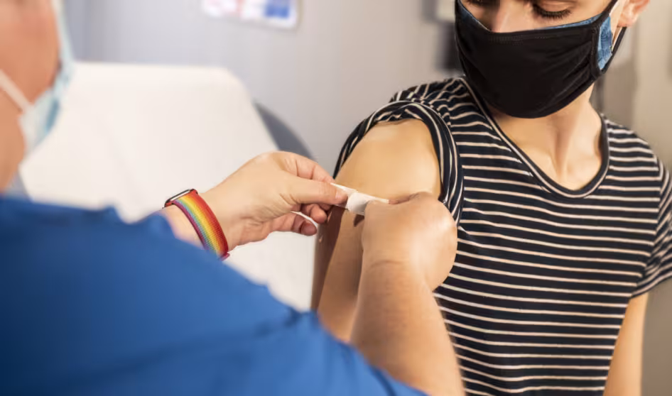 A health-care provider places a bandage on the injection site of a patient who just received a vaccine.