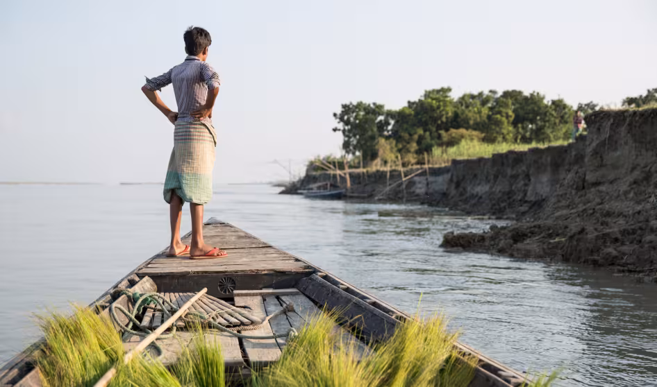 A boy on a boat in a Bangladeshi community affected by river erosion