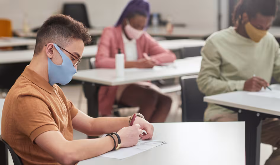 Side view portrait of young man and two other students taking a test