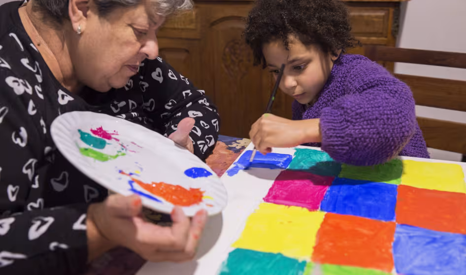 A grandmother and young grandchild painting at home