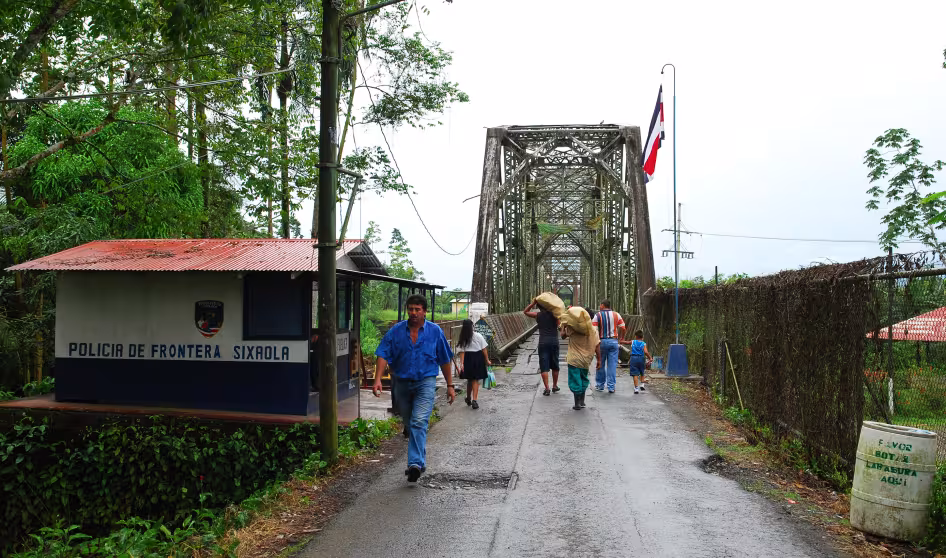 People walking across the bridge over the Sixaola River at the border between Panama and Costa Rica