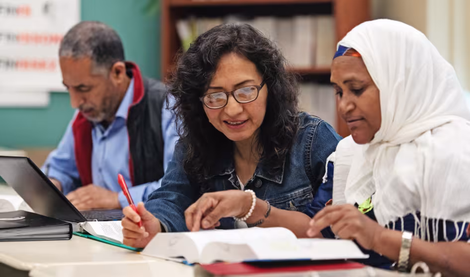 Immigrant adults working together at a long table in a classroom