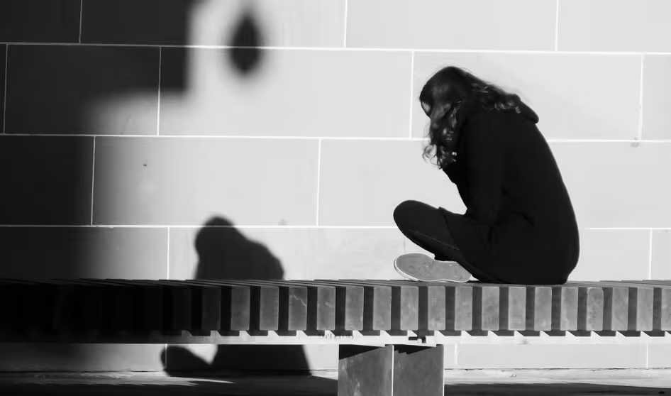 Girl sitting on a bench facing a wall
