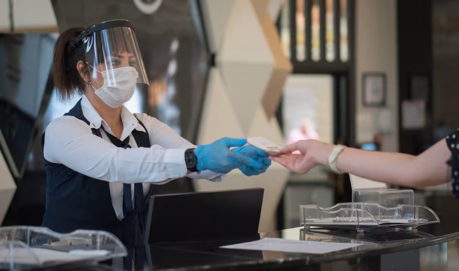 Receptionist wearing personal protective equipment while interacting with a customer