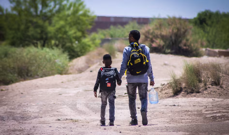 Father and son walk in front of the wall that divides Mexico from the United States