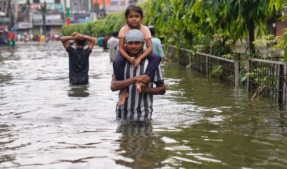 A father carrying his child through floodwater in Bangladesh
