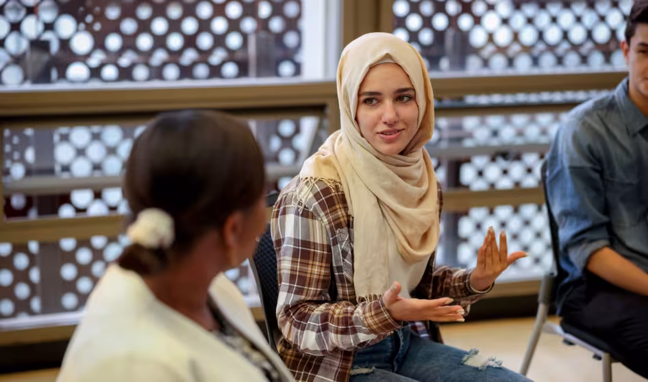 A college student in a hijab talks to another woman