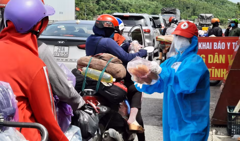Volunteer hands out food to migrant workers returning to their hometowns in Vietnam