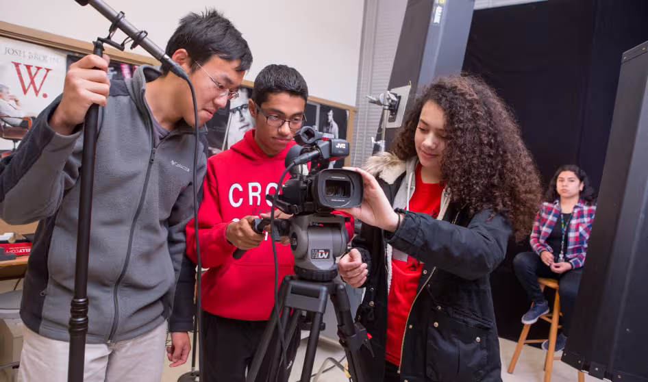 Three students in a digital filmmaking class set up a camera