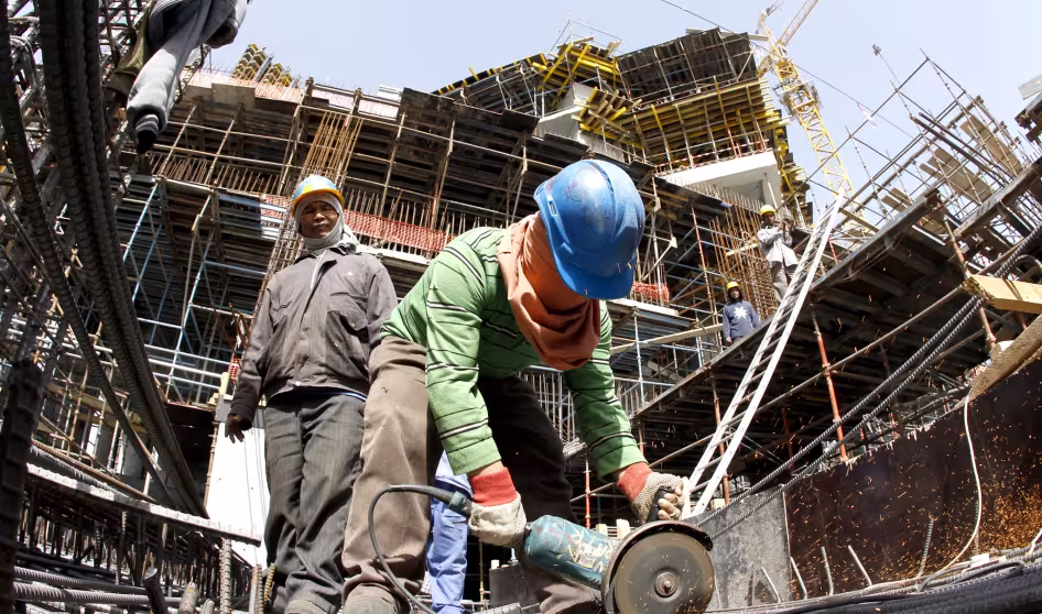A migrant worker cuts through a metal rod at a construction site in Qatar