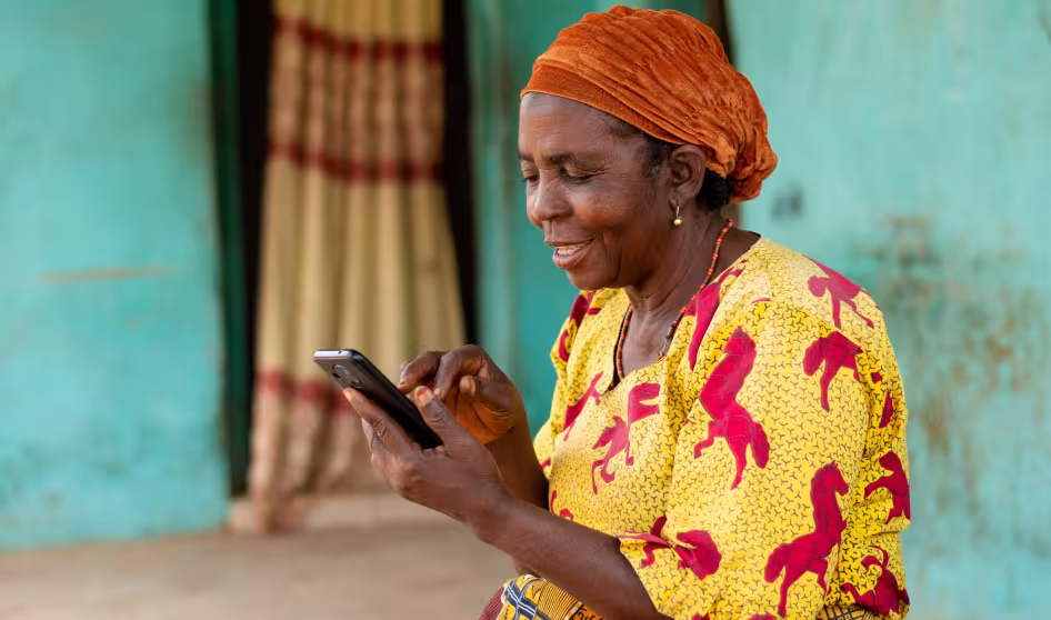 A woman in Nigeria smiles while using her mobile phone
