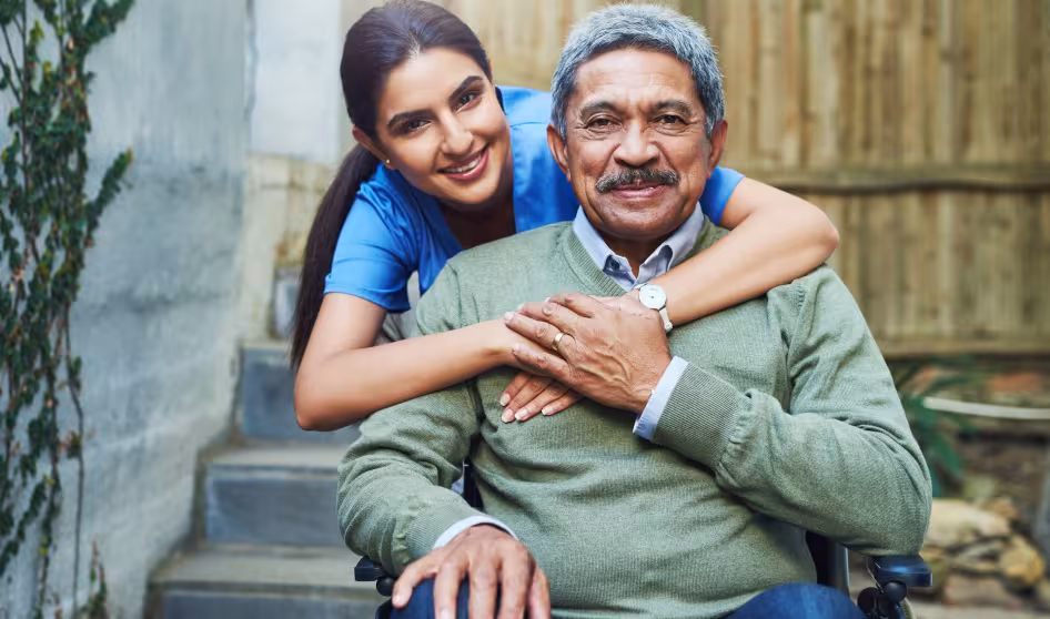  A young nurse hugs an elderly patient in a wheelchair