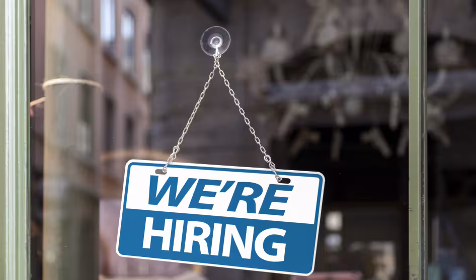 A blue "we're hiring" sign on a window