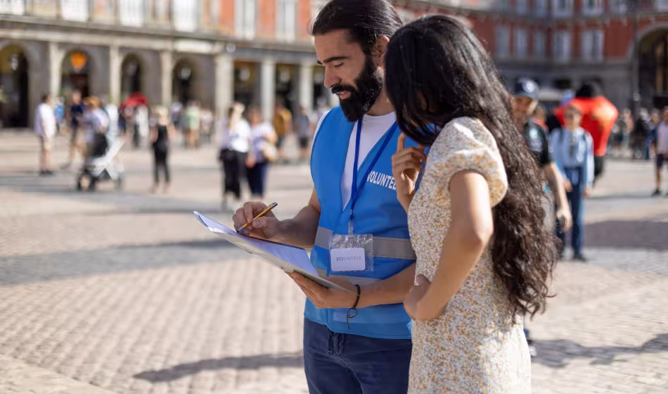 Volunteer talks to woman and writes on a clipboard in Madrid