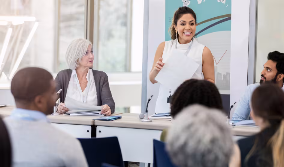 Young woman speaks to other participants at a meeting
