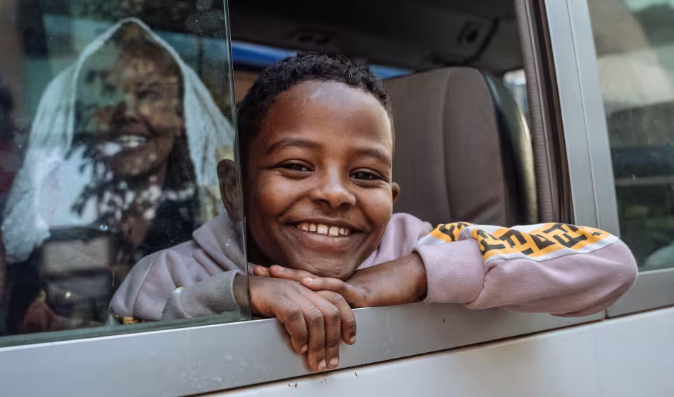 Young boy smiles out the window of a bus at a transit center in Ethiopia