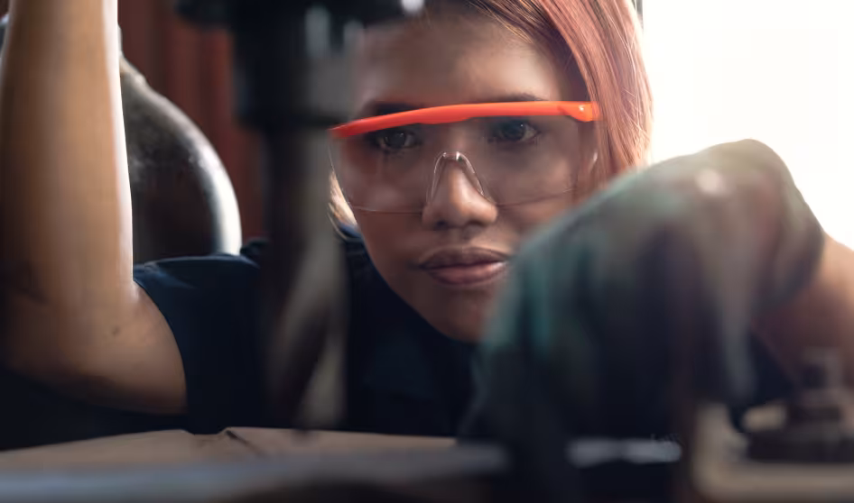 A young woman operating an industrial drilling machine