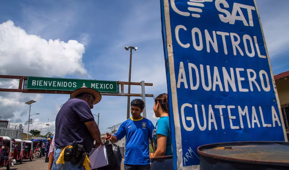 Two men and a young woman standing next to the Guatemala-Mexico border