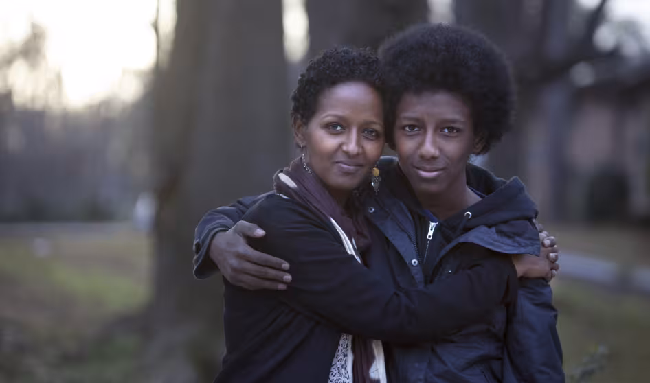 An Ethiopian resettled refugee mother and her son in the United States, where she works as a caseworker with other refugees