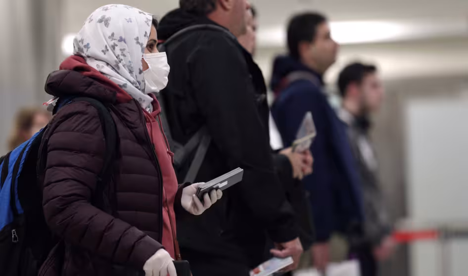 Travelers arrive at a U.S. airport wearing masks during the COVID-19 pandemic