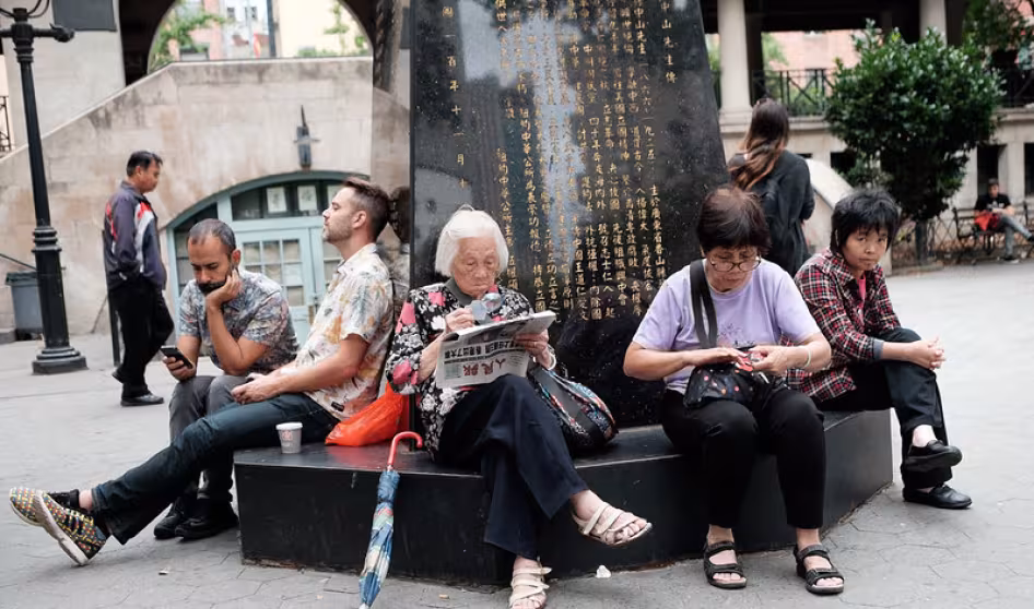 Group of people sit in a park in New York's Chinatown
