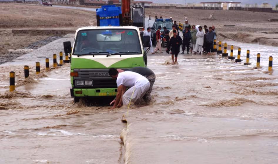 People pulling vehicles from a flooded road in an Afghan village